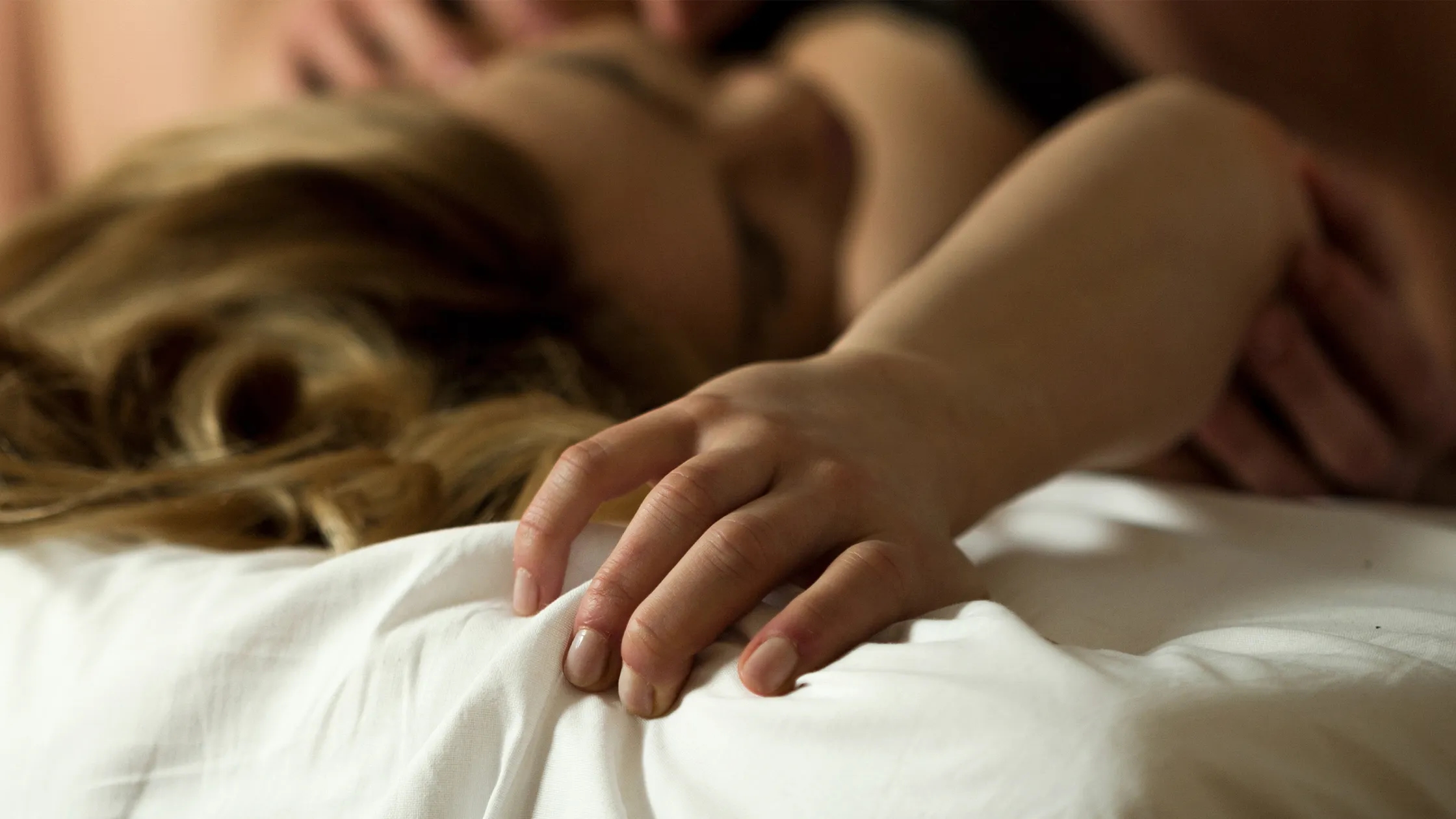 Couple enlacé dans un lit, symbole de la complicité et de l'excitation retrouvées sur NetAdultere.fr